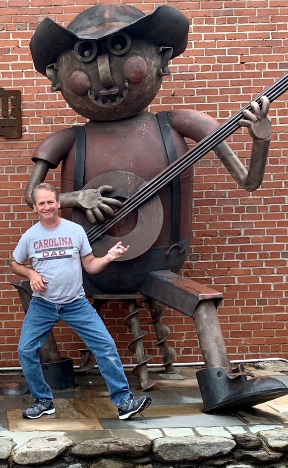 Brian posing with a giant metal banjo-player sculpture in Waynesville, North Carolina